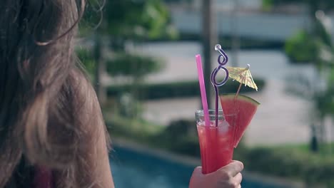 girl-holds-drink-in-glass-with-straws-and-watermelon-slice