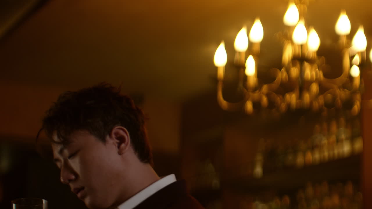 Alone at bar, Asian man holding a drink in dimly lit ambiance