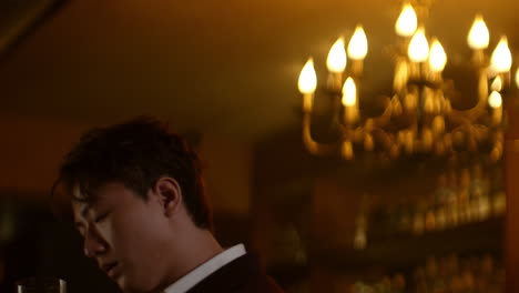 alone at bar, asian man holding a drink in dimly lit ambiance