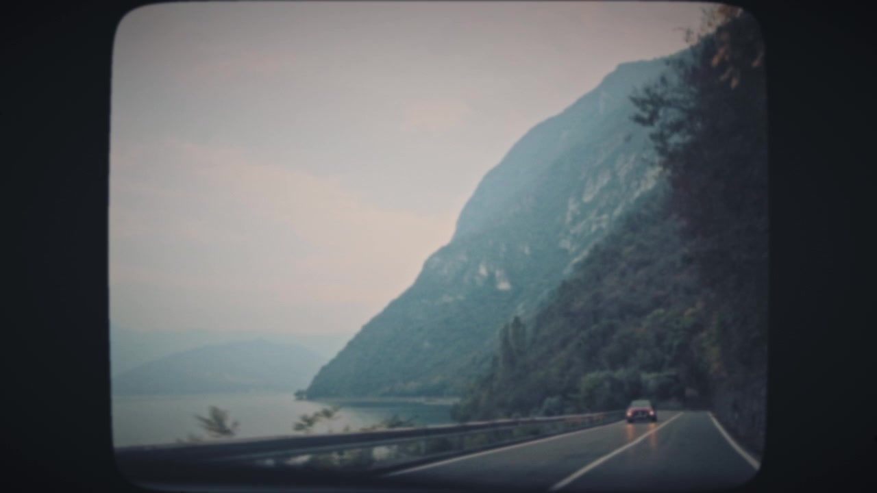Guidare lungo un lago e alte montagne