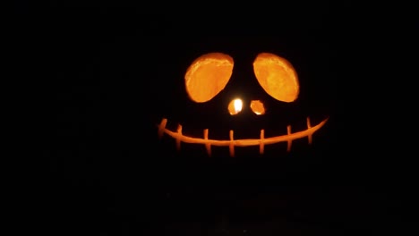 close up sliding shot of a carved orange pumpkin with light candle inside in the dark for the halloween decoration