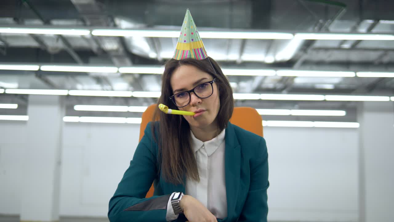 una triste trabajadora de oficina con un sombrero festivo está lanzando confeti.