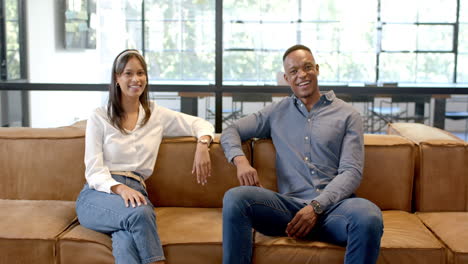 smiling business colleagues sitting on couch, relaxing during office break