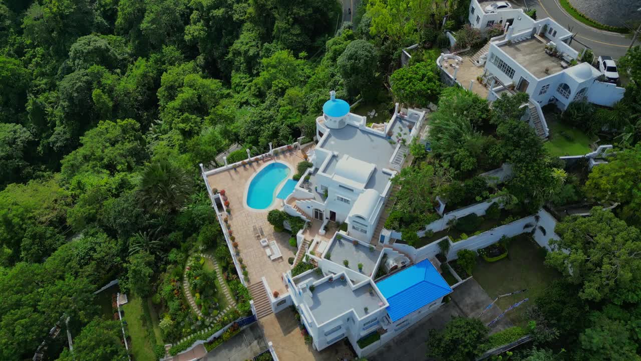 A rising tilt-down aerial of Villa Nonita with white walls and blue domes evoking Greek colors in the architecture in Talisay, Batangas, Philippines