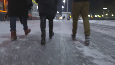 people walking on icy snow-covered street at night