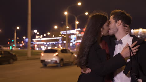 couple wearing stylish clothes kissing while they walking in the street after the new year's party