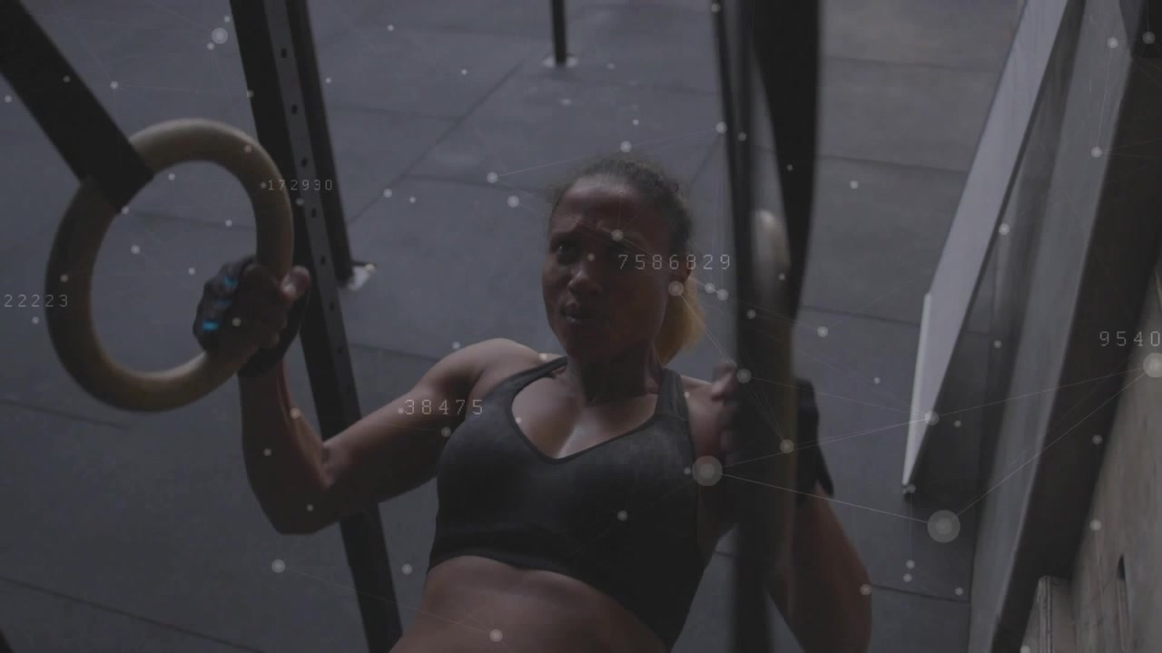 Female athlete gripping wooden rings and pulling torso upward, gym overlays tracking reps and power
