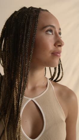 studio portrait shot of young woman with long braided hair recording beauty video