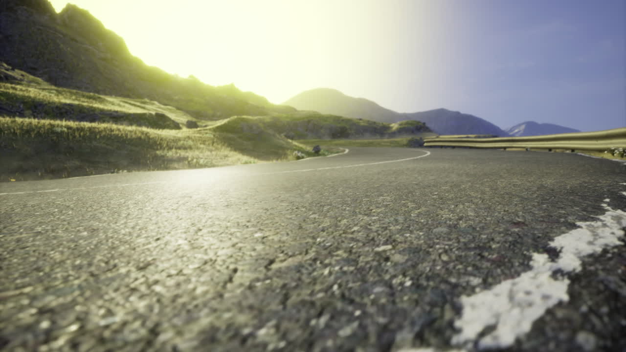 Serene mountain road winding through green hills under a bright sun