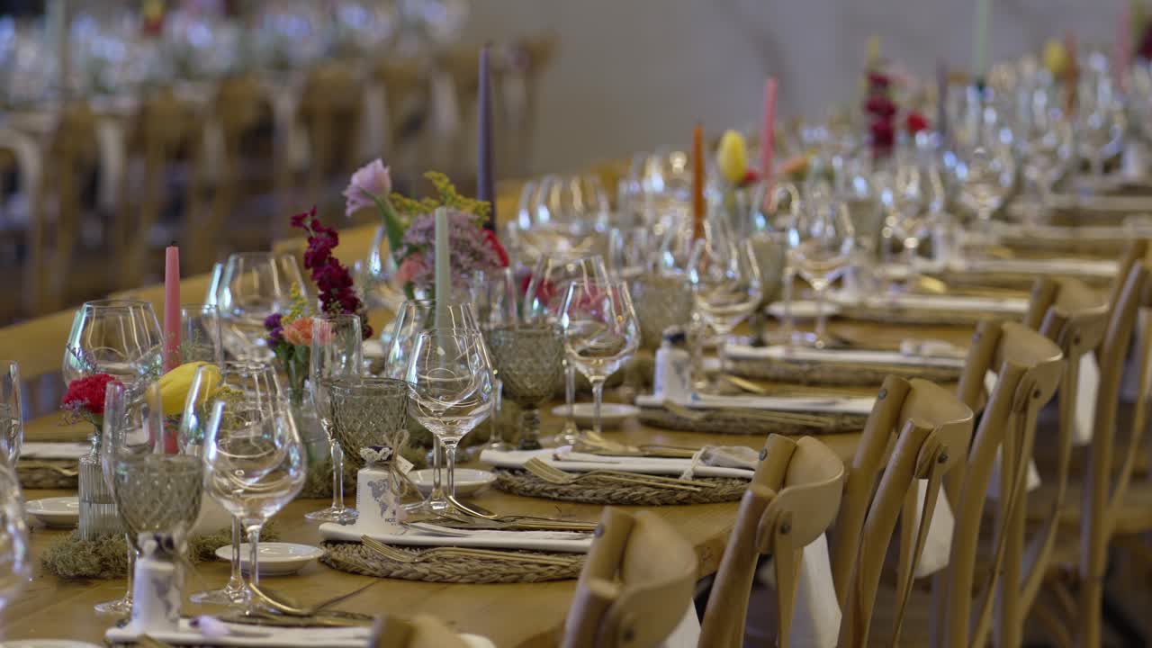 Long wedding banquet table with floral arrangements, candles, and glassware