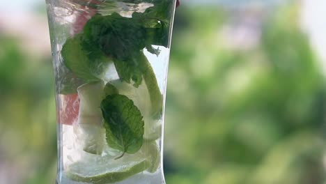 une paille macro orange mélange un cocktail de mojito avec des tranches de citron vert