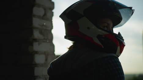 head view of a lady in a helmet, with sun light reflecting through the visor as she gazes to the right