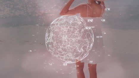 animación de globo digital y números girando sobre la vista trasera de una mujer con sombrero de pie en la orilla