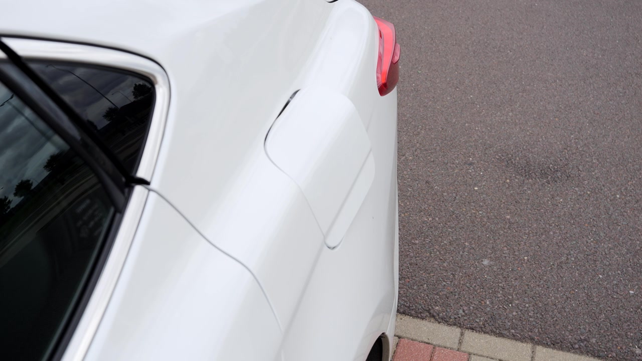Primo piano dello sportello del serbatoio di un'auto che si apre prima del rifornimento