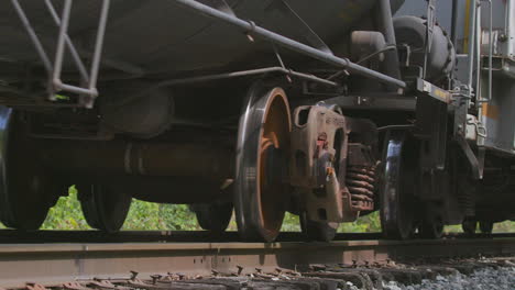 primer plano de ángulo bajo de las ruedas de los vagones de tren de mercancías y los coches que pasan por la cámara