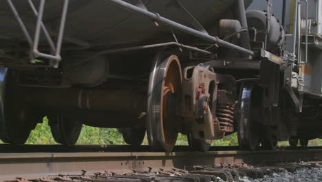 low angle closeup of freight train car wheels and cars passing by camera