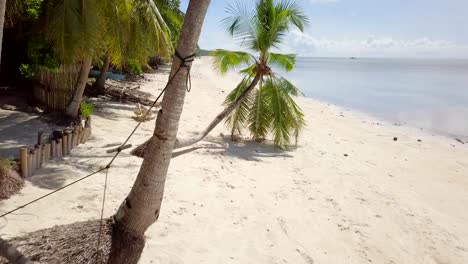 drone shot aerial view of young man relaxing on hammock by the beach, tropical climate. people travel vacations relaxation concept. 4k resolution video, shot in the philippines