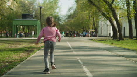 Fröhliches-Kleines-Mädchen-Rennt-Winkend-Die-Straße-Entlang-Im-Garten