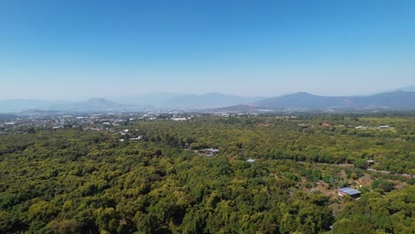 Punto-De-Vista-Aérea-De-Las-Montañas-Y-La-Pequeña-Ciudad,-Mientras-Se-Cierne-Sobre-árboles-De-Aguacate-Hass-En-México-Michoacán