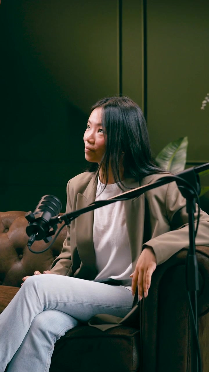 Tecnico che regola il microfono per una donna seduta in studio.