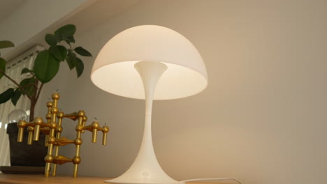 lámpara blanca moderna con una estructura dorada en un estante de madera