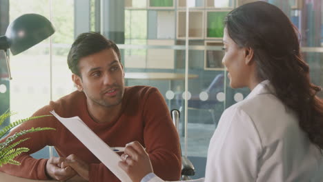 female doctor in office discussing test results with male patient in wheelchair in hospital