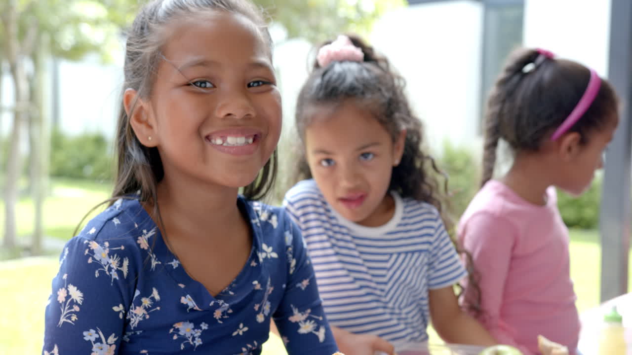 In school, three children smiling and enjoying outdoor lunch together