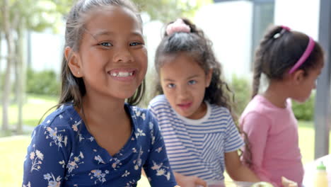 in school, three children smiling and enjoying outdoor lunch together