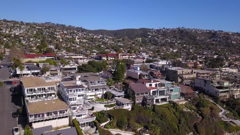 4K-Panning-Drone-Shot-of-Beach-and-Homes-in-Laguna-Beach,-California-on-a-Warm-Sunny-Day-over-the-Pacific-Ocean