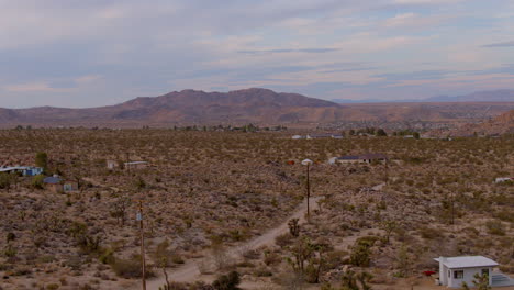 Small-houses-and-a-dirt-road-in-Joshua-Tree-with-a-beautiful-mountain-on-the-horizon