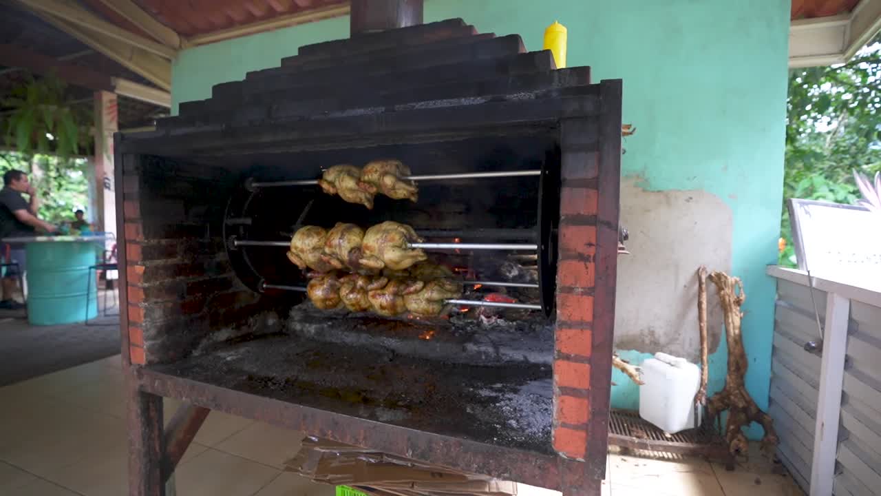 pollos girando en la rotisserie de la estufa de leña en el restaurante de costa rica