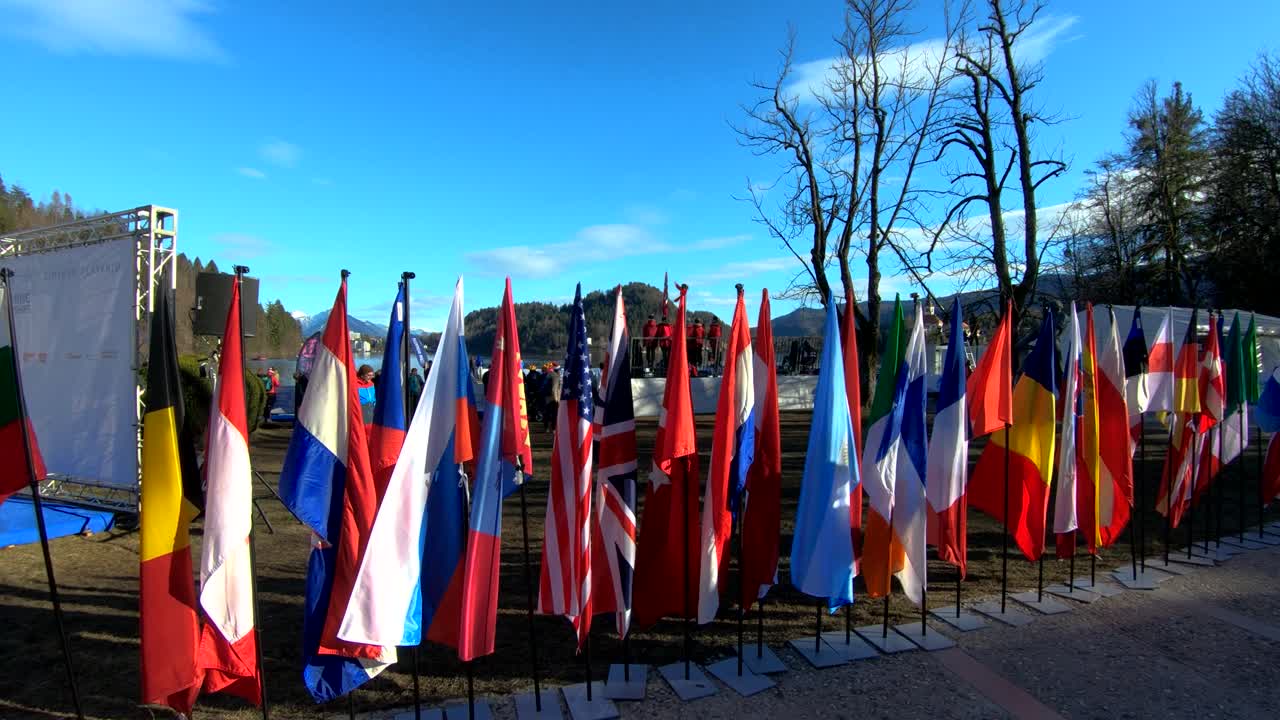Backward dolly moving flags and people swimmers Winter swimming world championship in lake Bled, Slovenia