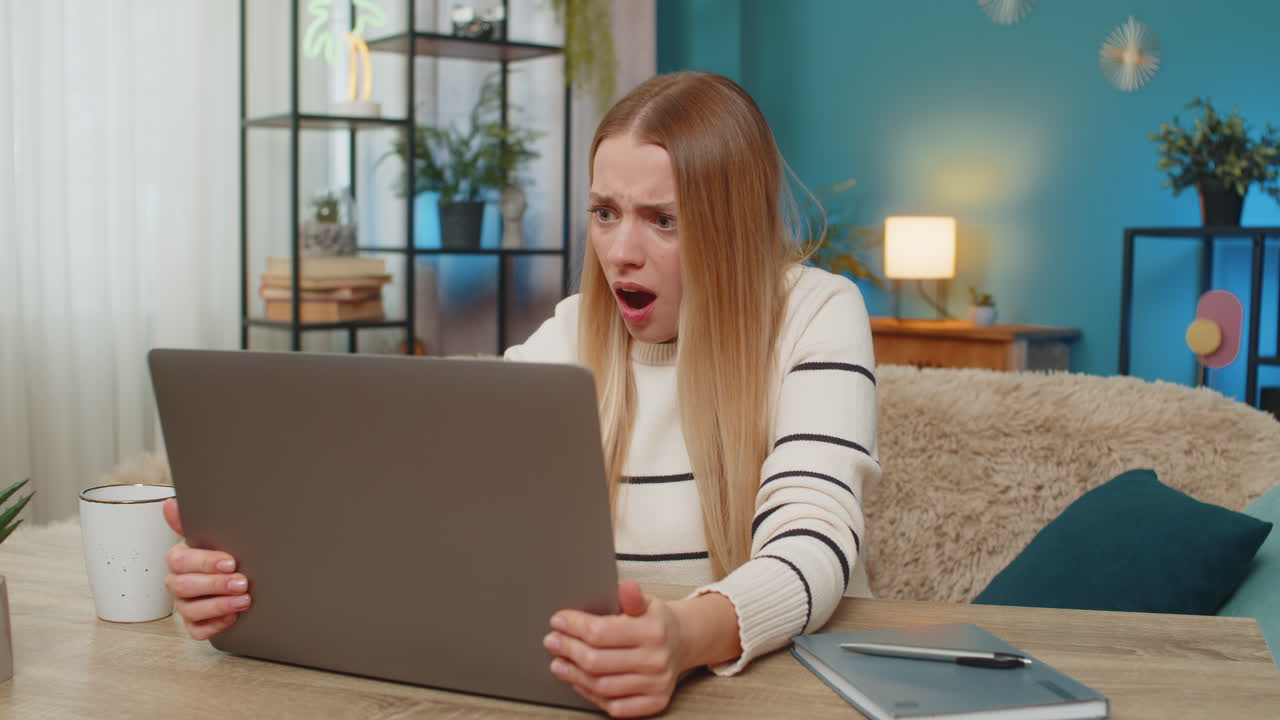 Caucasian woman facing virus error on laptop at home on table confused losing data frustrated