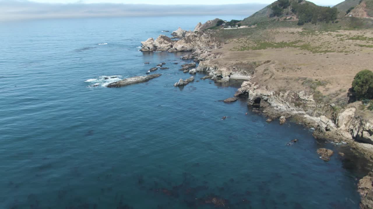 Up reveal aerial of Notleys Landing Viewpoint of the Pacific Ocean crashing waves on the rocky cliffs near Highway 1 in California, USA