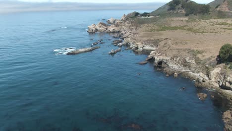 up reveal aerial of notleys landing viewpoint of the pacific ocean crashing waves on the rocky cliffs near highway 1 in california, usa