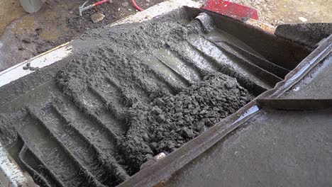 fluid concrete mix and pebbles poured into a formwork at a construction site