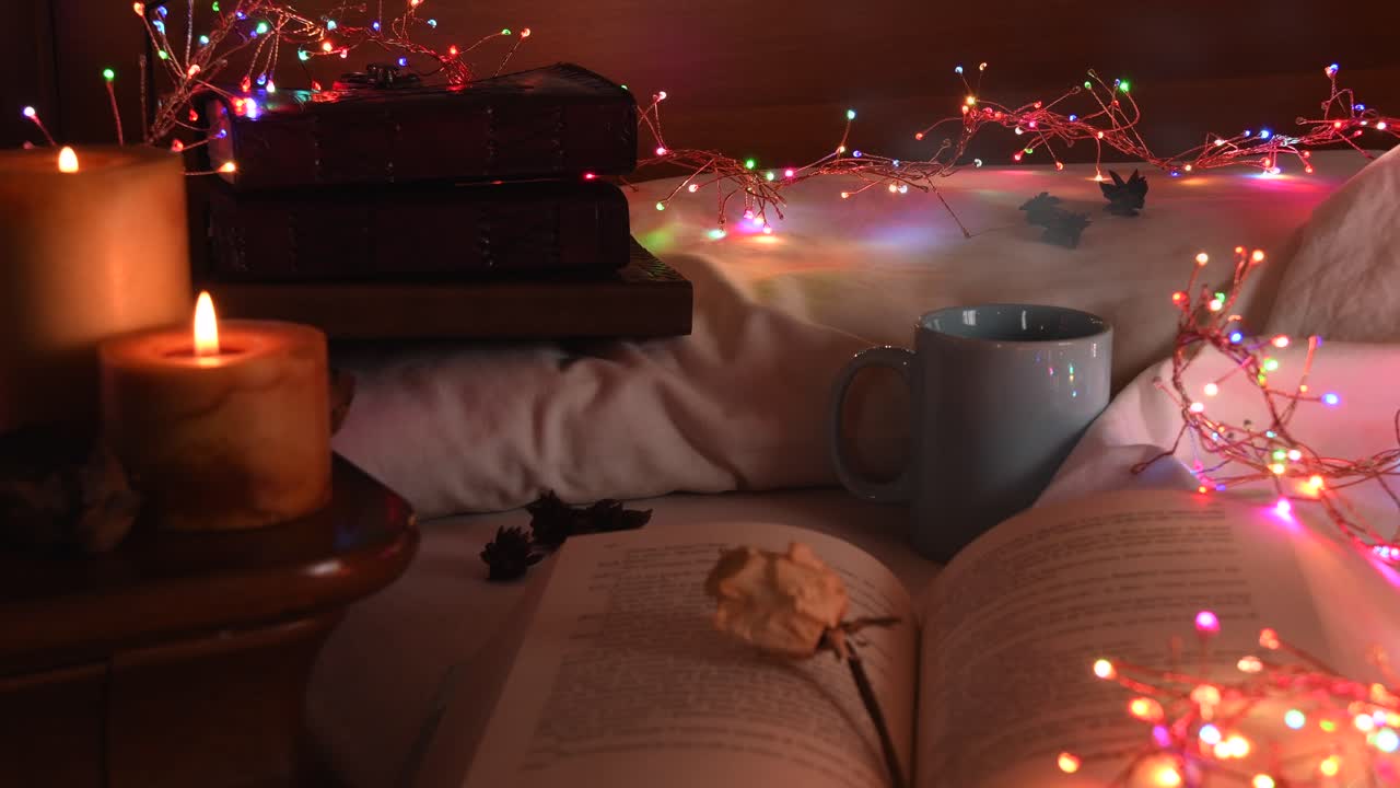 fondo acogedor de un libro abierto en una cama, al lado de una taza y rodeado de coloridas luces navideñas