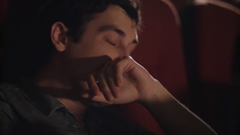 man yawning at cinema chair. handsome guy sleeping at cinema. yawning man asleep