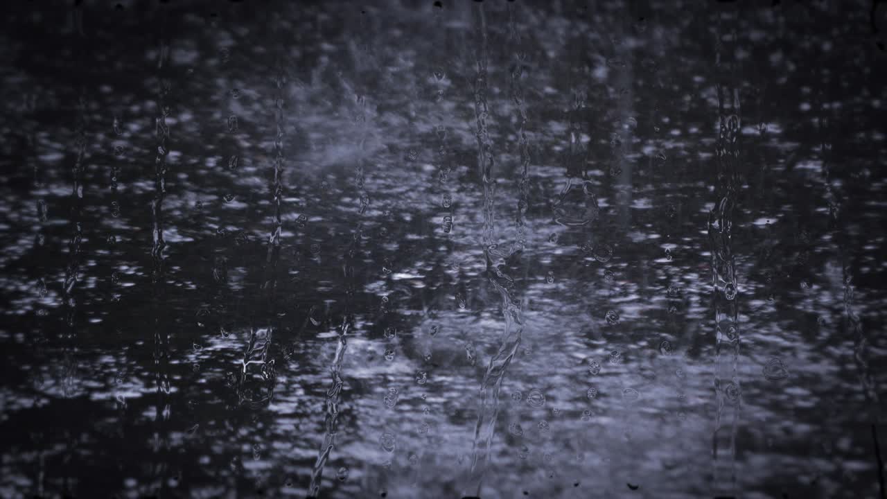 Heavy rain shower downpour cloudburst rainfall behind the glass.