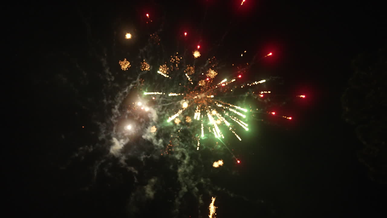 una serie de impresionantes y coloridos fuegos artificiales explotan en el cielo nocturno.