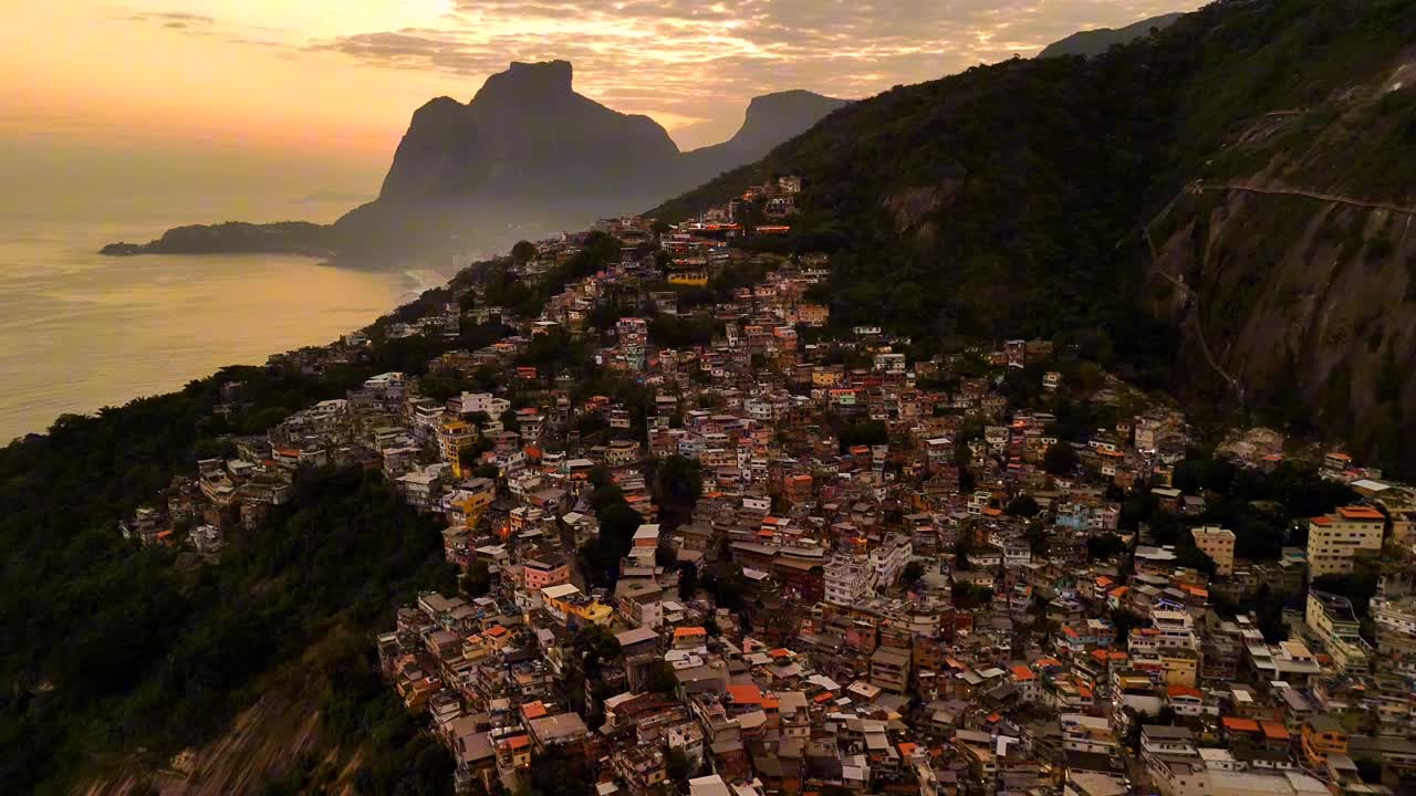 Experience Rio de Janeiro's Favela Vidigal at sunset: a breathtaking aerial drone shot showcasing vibrant houses, the glowing ocean, and majestic Dois Irmaos mountains under warm, golden hues