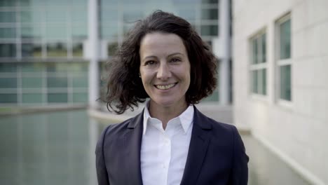 Smiling-curly-woman-wearing-formal-suit-looking-at-camera