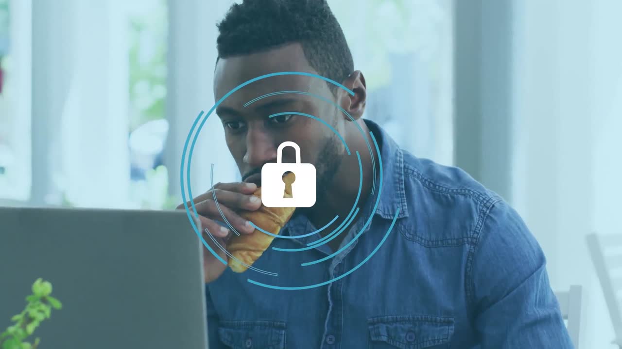 Animation of padlock with rotating circles over african american man working over laptop in office