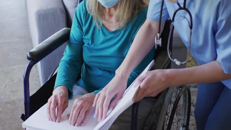 female health worker assisting senior woman to read braille book