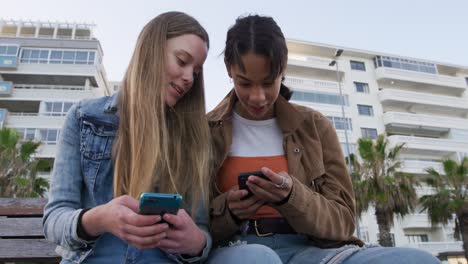 front view of a caucasian and a mixed race girl using their phones