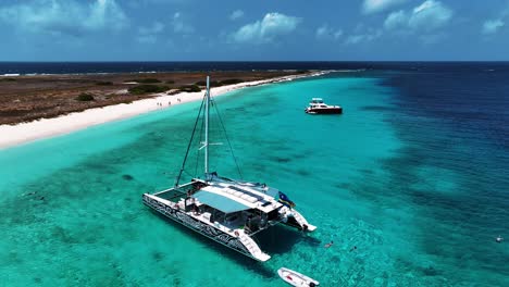 El-Dron-Se-Aleja-De-Un-Catamarán-Anclado-Cerca-De-Little-Curazao-Con-Agua-Azul-Clara-Y-La-Gente-Nada-En-Imágenes-Aéreas-De-Curazao-4k