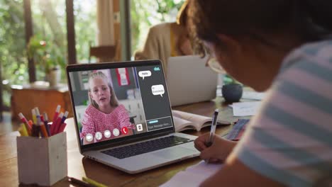 Schoolgirl-using-laptop-for-online-lesson-at-home,-with-her-colleague-and-web-chat-on-screen