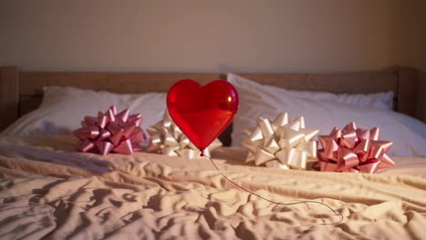 red heart balloon and gift bows on a bed