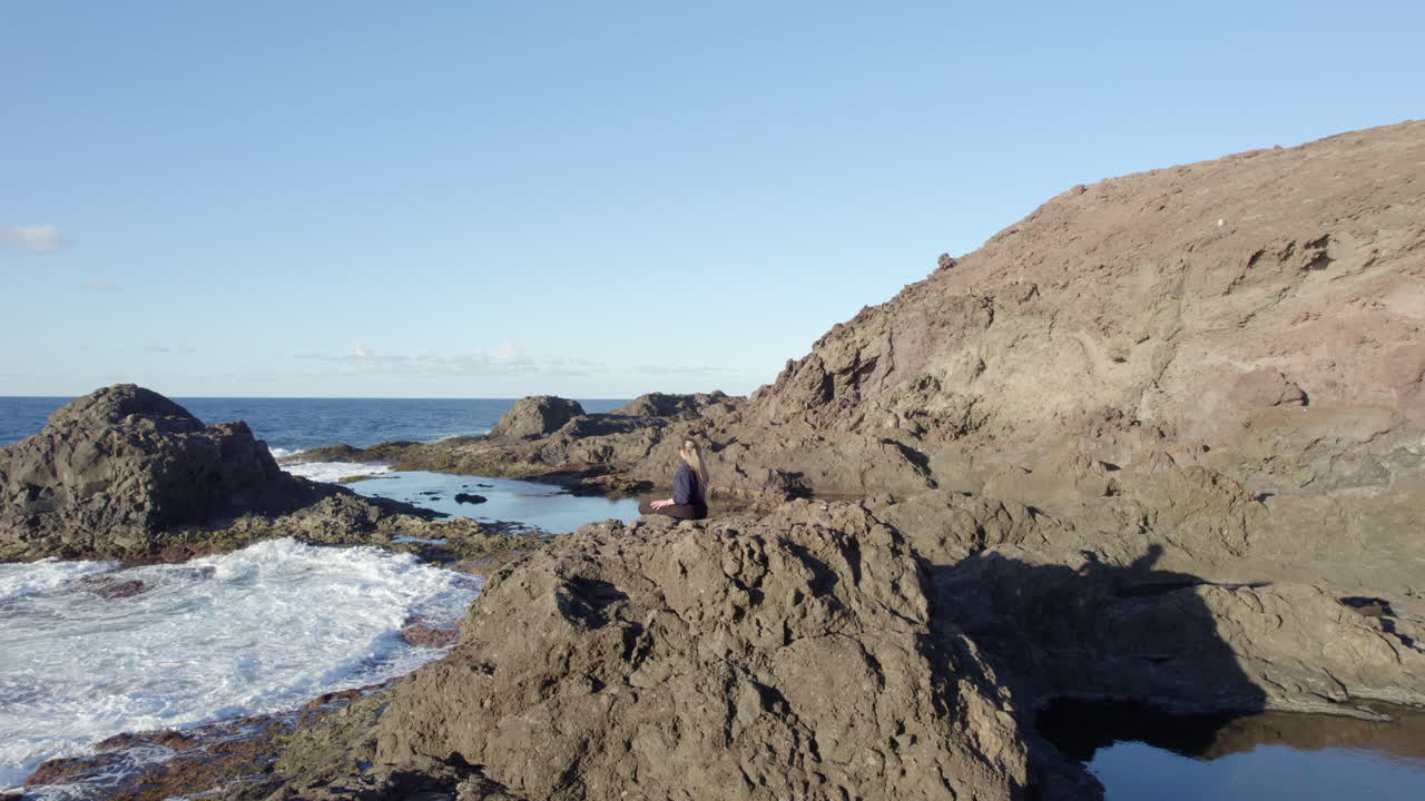 Woman enjoying a moment of mindfulness on the rocky coast of Gran Canaria