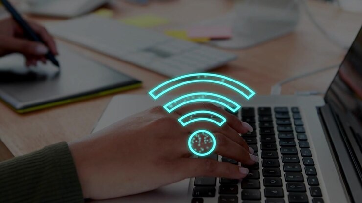Designer taster på bærbar computer og bruger stylus, hvilket får Wi-Fi-ikoner til at pulsere og viser forbindelse.
